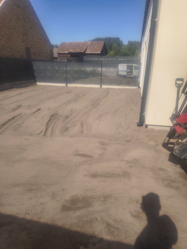 Wyrównana powierzchnia podwórka przy budynku po pracy minikoparki