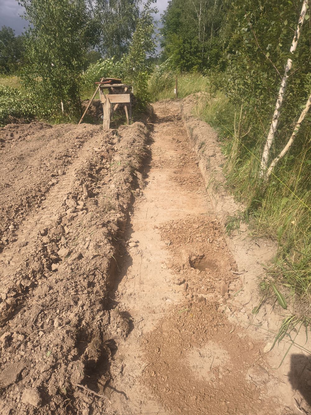Równy rowek pod podmurówkę ogrodzenia z urobkiem odłożonym wzdłuż wykopu