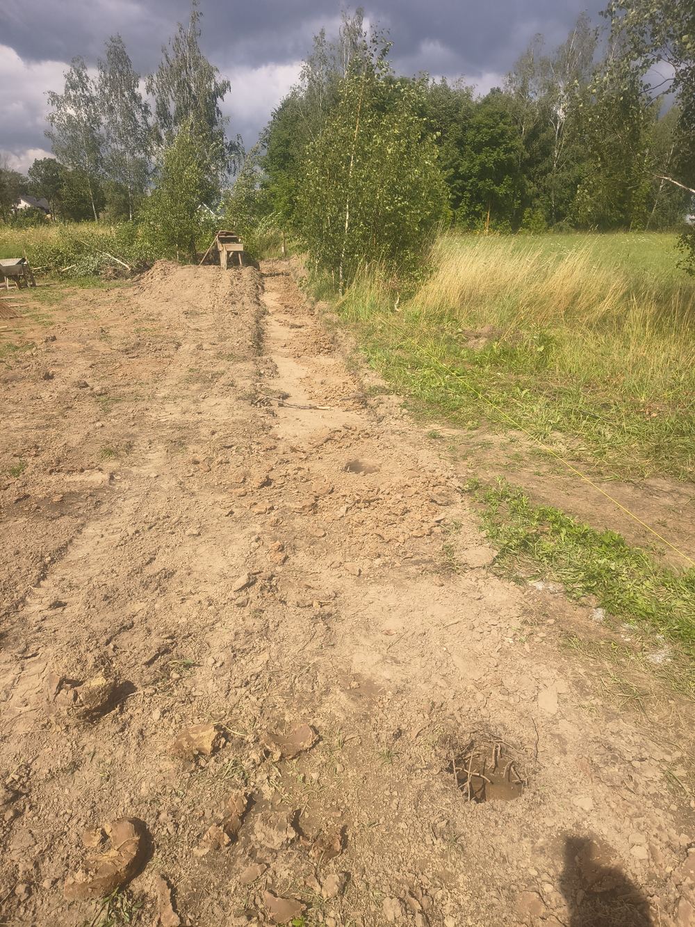 Wykorytowany pas gruntu pod ogrodzenie wzdłuż granicy działki, wykonany minikoparką