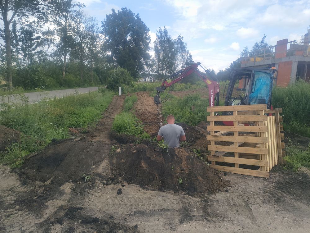Minikoparka z wiertnicą ślimakową podczas wiercenia otworów pod słupki ogrodzenia